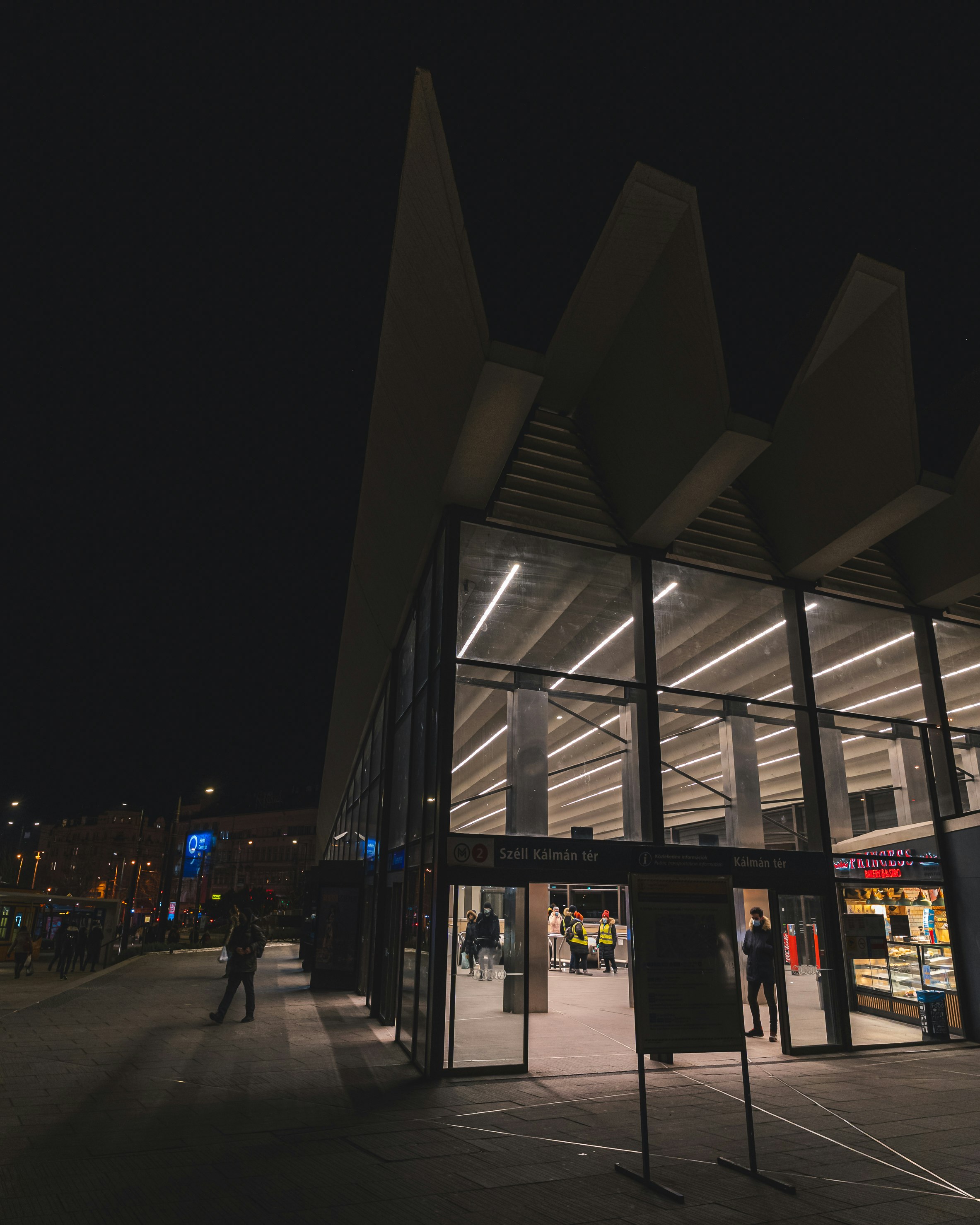 people walking on sidewalk near building during night time